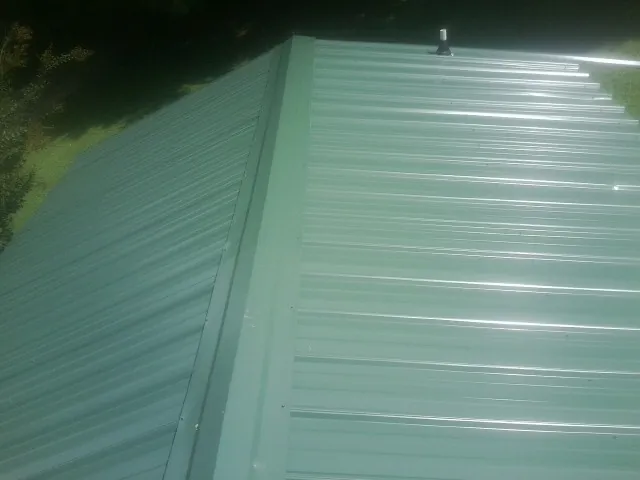 New green metal panels meeting at the ridge of a roof — Flat Roof Repair work by our crew in Camp Pendleton