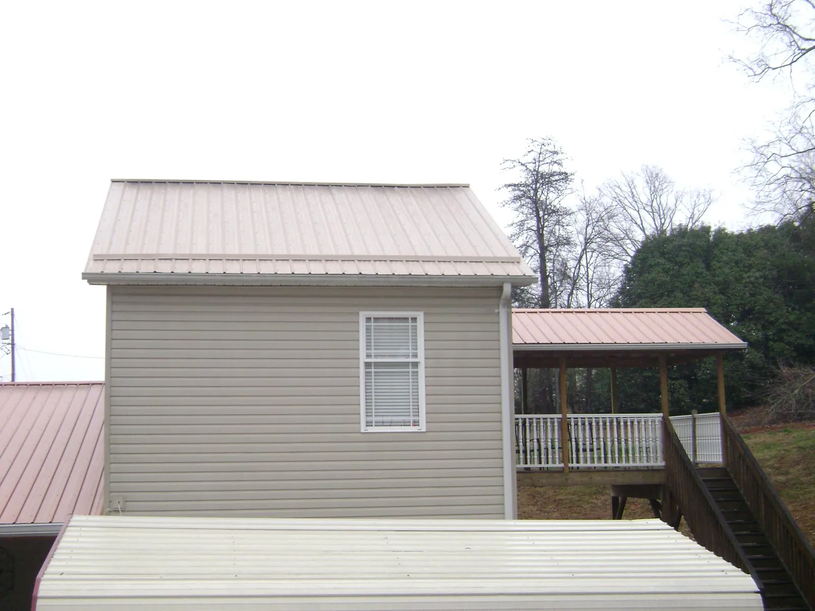 Tan metal roofs on a two story addition and attached porch, from a Roof Replacement job in Camp Pendleton