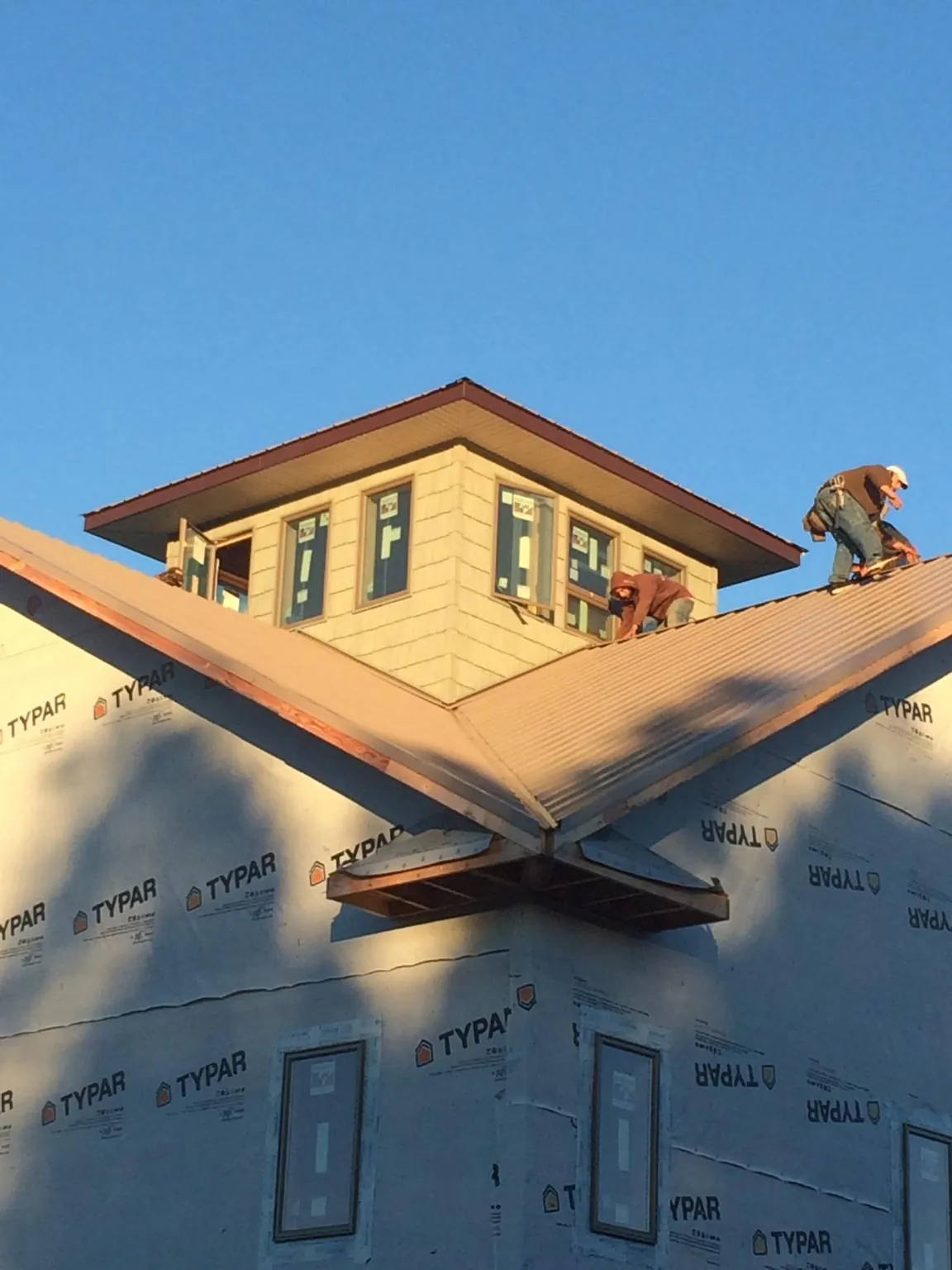 Roofers working around a rooftop cupola on a new metal roof at sunset — Roof Waterproofing in Camp Pendleton by Roofing Brothers